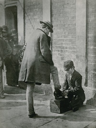 路上で男の靴を照らす若いシューブラック 作： English Photographer